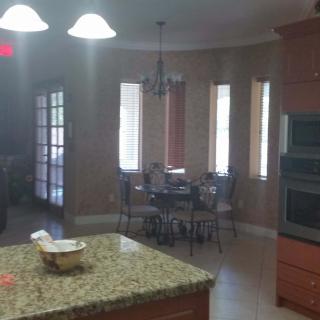 A kitchen with a granite countertop adjacent to a dining area with windows and a table.