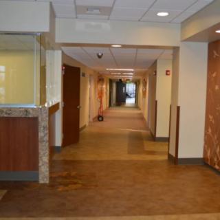 A long, well-lit hallway with carpet flooring and a reception area on the left.