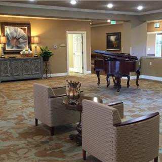 A spacious and elegantly decorated living room featuring a grand piano and comfortable seating.