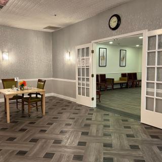 A modern waiting room with a seating area visible through open double doors.