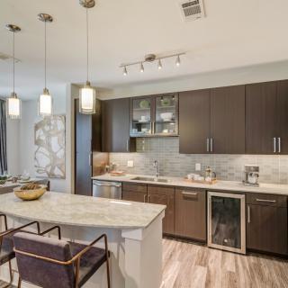 A modern kitchen with an open concept design featuring a central island, pendant lighting, and stainless steel appliances.