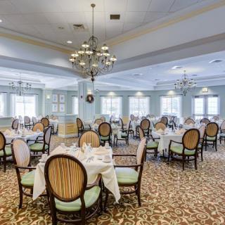 An elegant dining room with neatly arranged tables and chairs, adorned with chandeliers.