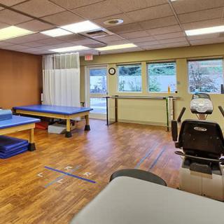 A physical therapy clinic with therapy beds and rehabilitation equipment.
