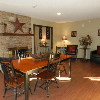 A cozy dining room with a wooden table, chairs, and a fireplace decorated with a star.