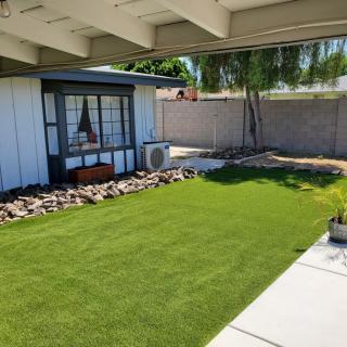 A modern backyard with artificial grass and clean landscaping under a shaded patio.