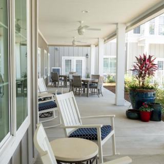A spacious porch with comfortable seating, ceiling fans, and decorative plants.