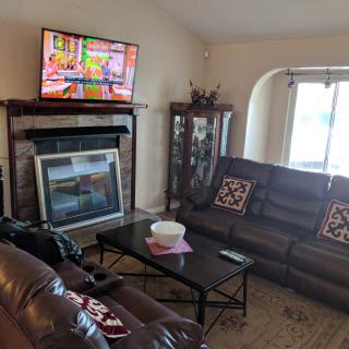 A cozy living room with a sofa, coffee table, and a TV mounted above the fireplace.
