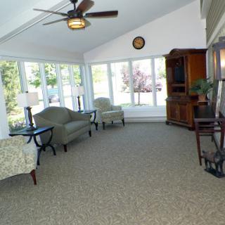 A bright and spacious sunroom with comfortable seating, large windows allowing natural light, and a ceiling fan.