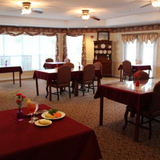 A cozy dining room with maroon tablecloths and neatly arranged tables and chairs.