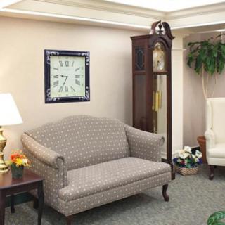 A cozy living room with a patterned sofa, a grandfather clock, and elegant decor.
