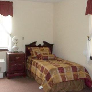 A simple bedroom with a single bed, nightstand, and window.