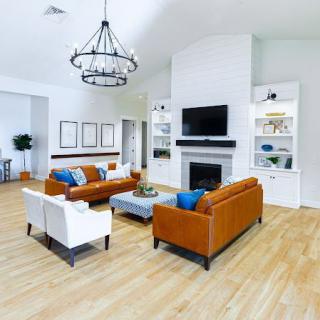 A modern living room with brown sofas and a sleek fireplace, complemented by a central chandelier.