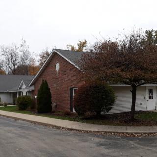 A suburban residential street with brick houses and trees lining the sidewalk.