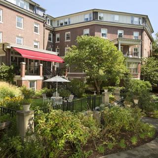 A beautiful residential apartment building with a lush garden and patio area.