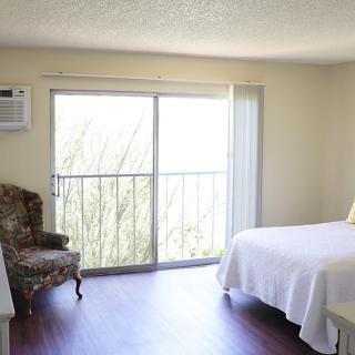 A minimalist bedroom with natural light and a small seating area.