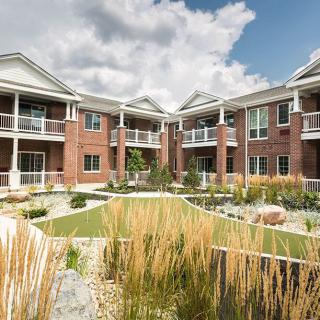 A modern apartment building with well-maintained landscaping under a cloudy sky.