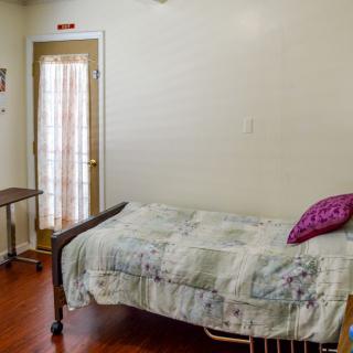 A simple hospital room with a bed and side table near a window with curtains.