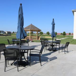 Outdoor patio area with tables, chairs, and umbrellas near a gazebo.