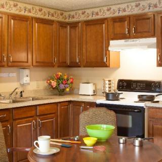 A cozy kitchen with wooden cabinets, a stove, and a dining area.