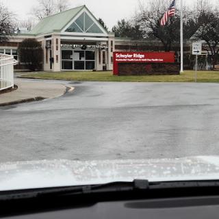 View of a building entrance with a sign and an American flag.
