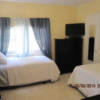 A cozy bedroom with twin beds, a television, and a window with curtains.