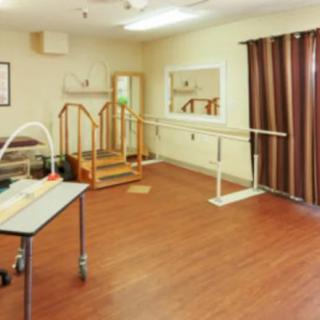 A rehabilitation room equipped with exercise equipment and a mirror.