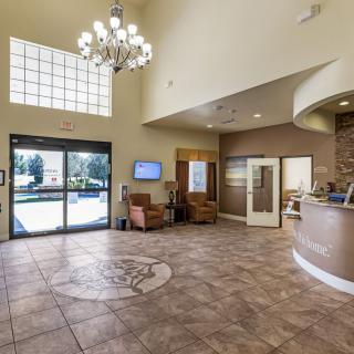 A spacious lobby with a chandelier, seating area, and a reception desk.