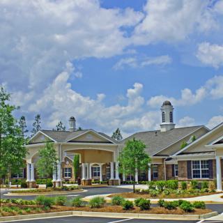 A scenic view of a large building complex under a partly cloudy sky with surrounding trees.