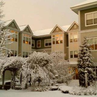 A snow-covered house with lit windows on a winter evening.