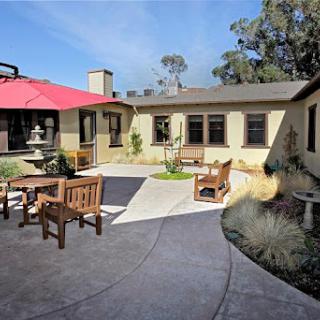 A serene outdoor patio area featuring comfortable seating and landscaped greenery.