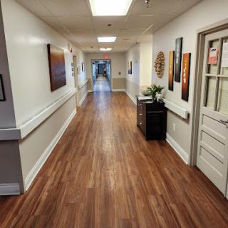 A well-lit hallway featuring wooden flooring and decorative artwork on the walls.