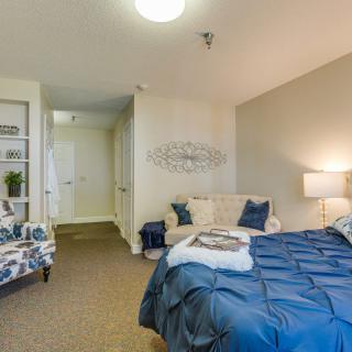 A cozy, modern bedroom featuring a neatly made bed with blue bedding, decorative pillows, and a lamp.