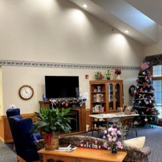 A cozy living room with a television, coffee table, and decorated Christmas tree.