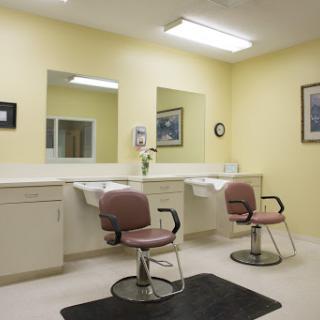 A clean and simple hair salon featuring two styling chairs, mirrors, and a bright yellow interior.