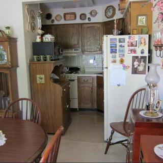 A cozy kitchen and dining area with traditional wooden furniture and a refrigerator adorned with magnets and photos.