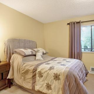 A cozy bedroom with a neatly made bed, soft lighting, and a window with curtains.
