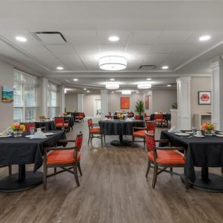 A modern dining room with neatly arranged tables and chairs, featuring warm lighting and contemporary decor.