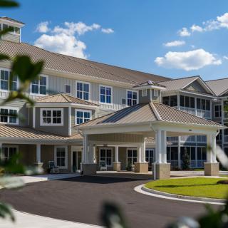 A large, multi-story residential building with a prominent entrance, surrounded by landscaped greenery.