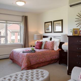 A cozy bedroom with stylish decor and a large window allowing natural light.