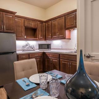 A modern kitchen and dining area featuring wooden cabinets, a refrigerator, and an elegantly set table with blue accents.