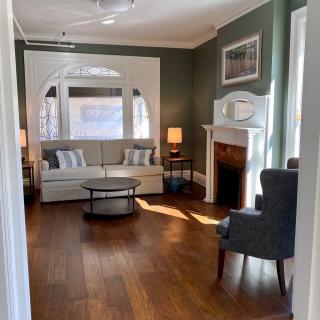 A cozy living room with a sofa, armchair, fireplace, and wooden flooring.