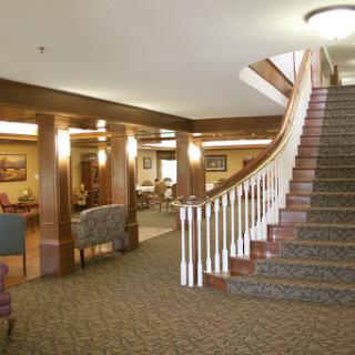 A spacious lobby featuring a grand staircase and comfortable seating areas, adorned with wooden accents.