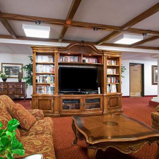 A cozy living room featuring a wooden entertainment center with bookshelves, a large television, and comfortable seating.