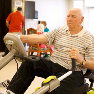 An elderly man engages in a fitness routine using exercise equipment.