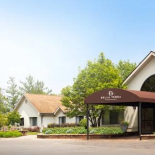 A charming building surrounded by lush greenery, featuring a spacious driveway.