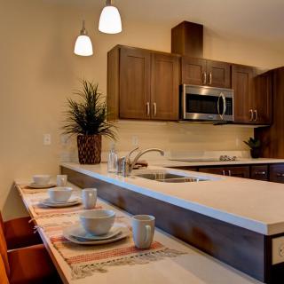 A modern kitchen with wood cabinets, stainless steel appliances, and a stylish dining area.