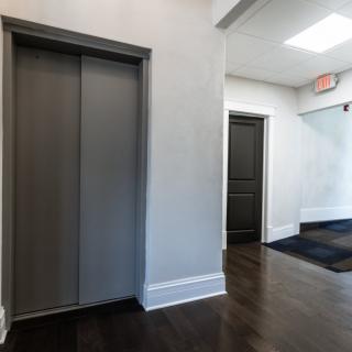 A hallway with an elevator and adjacent doors in a building interior.