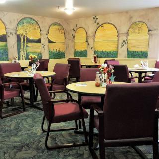 A cozy dining room with tables and chairs, adorned with a mural on the wall.