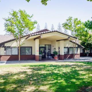 A suburban residential house with a well-maintained lawn and trees in the front yard.