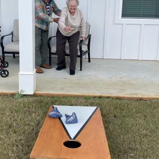Two seniors enjoying a game of cornhole outdoors.